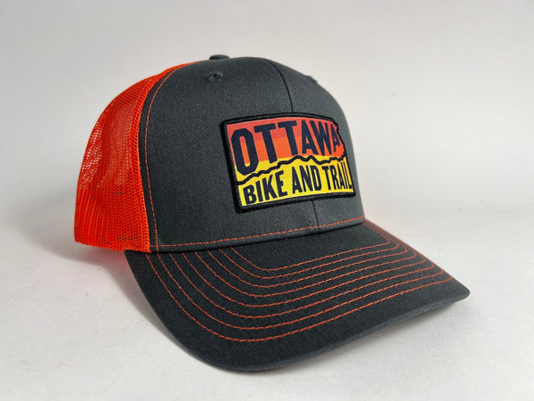 Ottawa Bike and Trail, LLC Shop Merch Slate Orange OBAT Logo Sunrise Trucker Hat